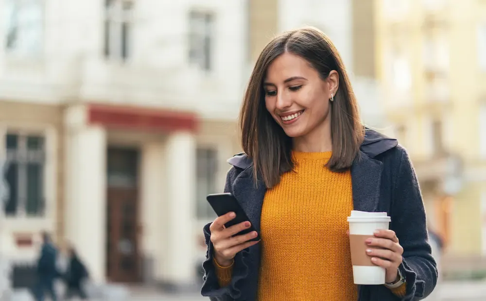 Woman with phone and coffee.